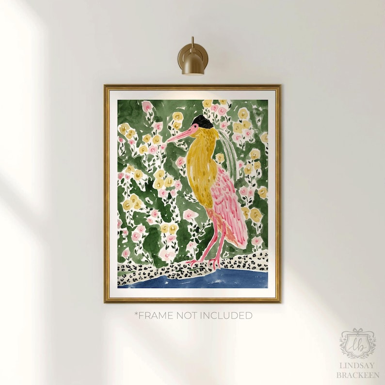 May include: A framed watercolor print featuring a stylized bird with yellow and pink plumage, set against a backdrop of green foliage and yellow and pink flowers. The artwork is in a gold frame and includes the text "*FRAME NOT INCLUDED".