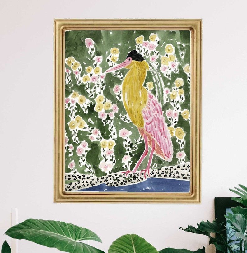 May include: Watercolor painting of a bird with yellow and pink plumage, set against a backdrop of green foliage and yellow and pink flowers. The bird stands on a blue and leopard print base, framed in gold.