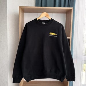 May include: Black sweatshirt with a yellow embroidered logo that says "Thompson Auto-Ordnance".