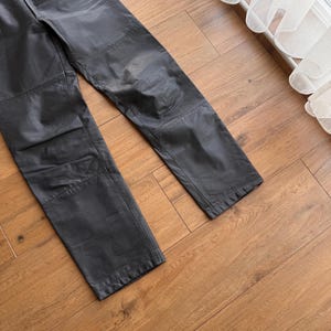 Pu&ograve; includere: Pantaloni in pelle nera con un classico design a gamba dritta. I pantaloni hanno un tradizionale stile a cinque tasche e pannelli rinforzati sulle ginocchia. La pelle ha un aspetto leggermente usurato.