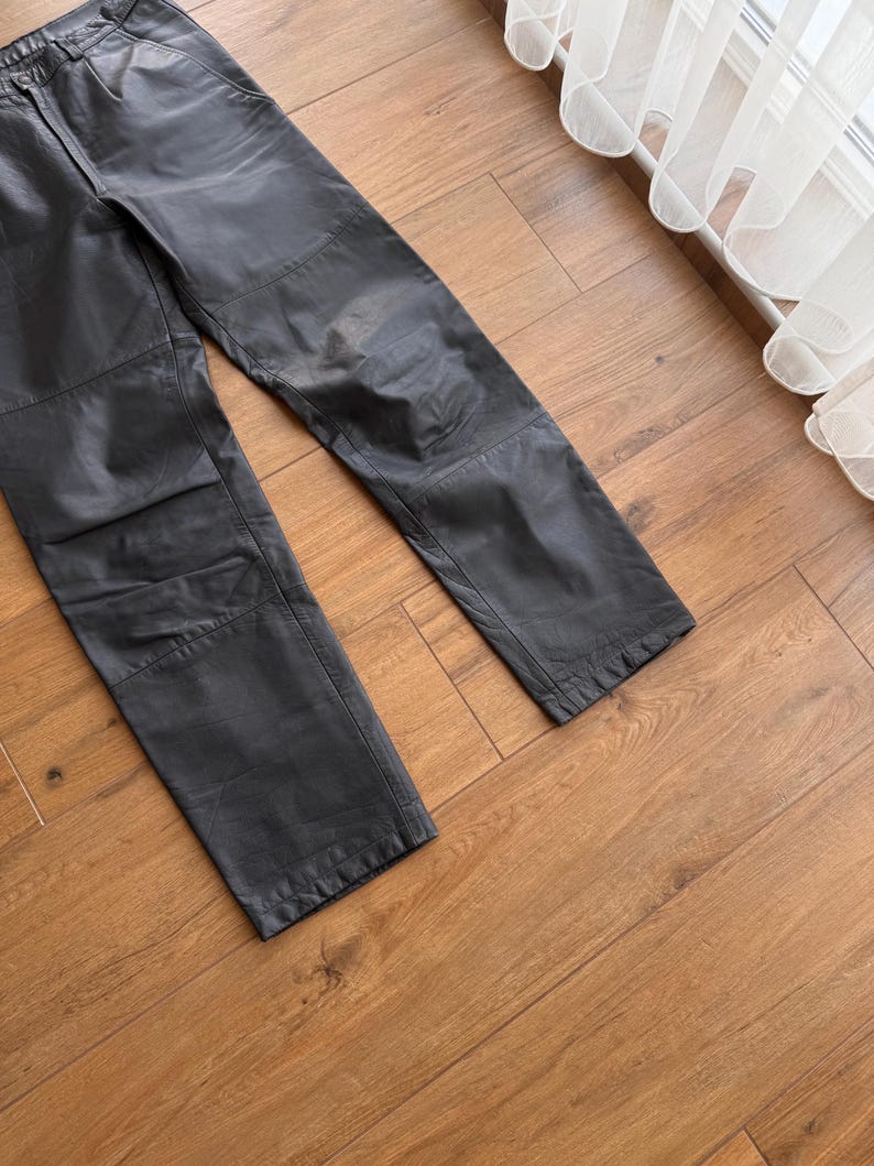 Pu&ograve; includere: Pantaloni in pelle nera con un classico design a gamba dritta. I pantaloni hanno un tradizionale stile a cinque tasche e pannelli rinforzati sulle ginocchia. La pelle ha un aspetto leggermente usurato.