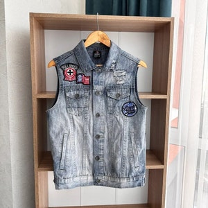 May include: A light blue denim vest with distressed details and multiple patches, including a "Full Speed" patch with a motorcycle symbol, a red, white, and blue patch, and a "Live Fast" patch with a motorcycle symbol.