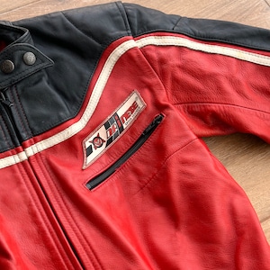 May include: Red leather motorcycle jacket with black and white racing stripes and a Dri-Mex Speed Leather patch on the left chest.
