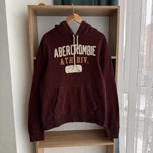May include: A maroon hooded sweatshirt with the text "Abercrombie Ath Div." in white and brown lettering.