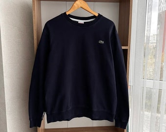 May include: A dark blue crew neck sweatshirt with a green crocodile logo on the left chest.