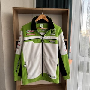 May include: A green, white, and black zip-up jacket with multiple sponsor logos, including "Castrol" and "Honda Gresini." The jacket has a stand-up collar and a full-length zipper. The text "GO & FUN" is visible on the right chest.