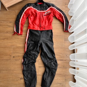 May include: A red and black leather motorcycle suit with white stripes. The jacket has a zipper closure and a patch on the left chest that says "No Fear".