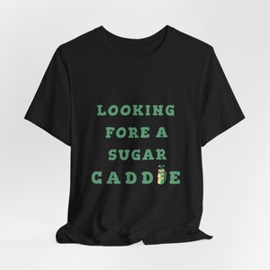 May include: Black t-shirt with green text that reads "Looking Fore A Sugar Caddie" with a green and brown golf bag icon.
