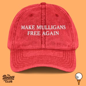 Peut inclure: Casquette de baseball rouge avec le texte blanc "MAKE MULLIGANS FREE AGAIN". La casquette a une visière incurvée et un bouton sur le dessus. Le logo The Bounce Club est en bas à gauche.