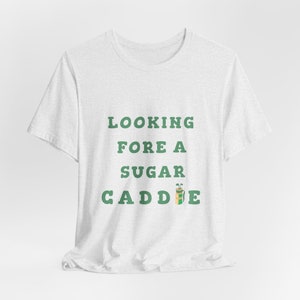 May include: White t-shirt with green text that reads "Looking Fore A Sugar Caddie" with a green and brown golf bag icon.