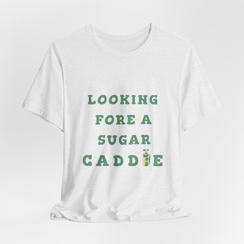 May include: White t-shirt with green text that reads "Looking Fore A Sugar Caddie" with a green and brown golf bag icon.