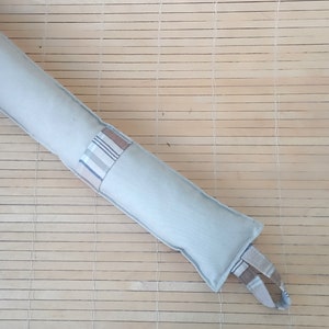 May include: A light gray doorstop with a brown and white plaid fabric panel. The doorstop has a loop handle for easy carrying.