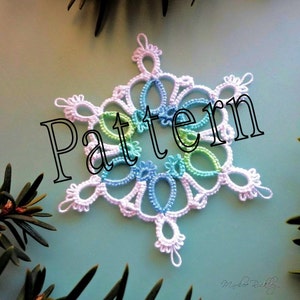 May include: A delicate crocheted snowflake in shades of white, blue, and green. The snowflake is a pattern for crocheting.