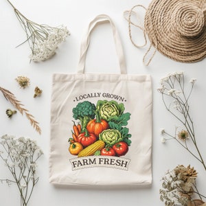 May include: A white canvas tote bag with the text "Locally Grown. Farm Fresh" printed in brown. The bag features a colorful illustration of fresh vegetables, including broccoli, cauliflower, corn, tomatoes, and pumpkins.