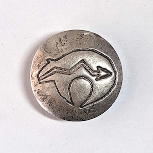 May include: A small, round, silver-toned button with a raised design. The design features a stylized animal shape with a zig-zag line and an arrow. The button has a slightly distressed, vintage appearance. The Etsy shop name "seriousbeader.etsy.com" is printed at the bottom.