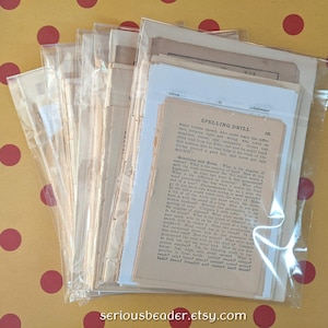 May include: A collection of vintage paper ephemera, including pages from a book titled "Spelling Drill", packaged in clear plastic sleeves. The papers have a warm, aged tone, with visible text and a few illustrations. The Etsy shop name is visible at the bottom.