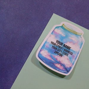 May include: A sticker of a glass jar with a blue, pink, and white watercolor sky inside. The jar has a black label with the text "YOUR NAME YOUR STREET ADDRESS YOUR CITY, STATE ZIPCODE".