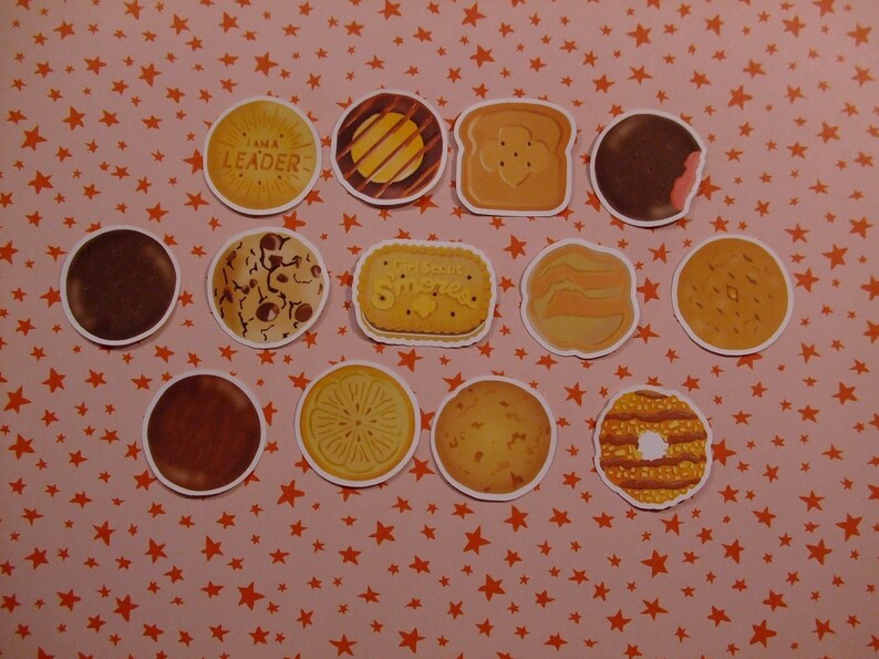 Op de afbeelding: Een verzameling van 12 Girl Scout cookie stickers, met verschillende smaken zoals Thin Mints, Samoas en Tagalongs. De stickers zijn gerangschikt op een roze achtergrond met oranje sterren.