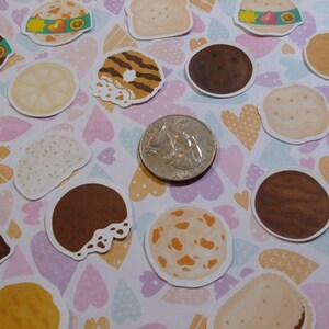 Pu&ograve; includere: Assortimento di adesivi per biscotti colorati con vari disegni, tra cui un biscotto al cioccolato, un biscotto al burro di arachidi, un biscotto al burro e un biscotto al limone. Gli adesivi sono disposti su uno sfondo bianco con cuori rosa, blu e gialli.
