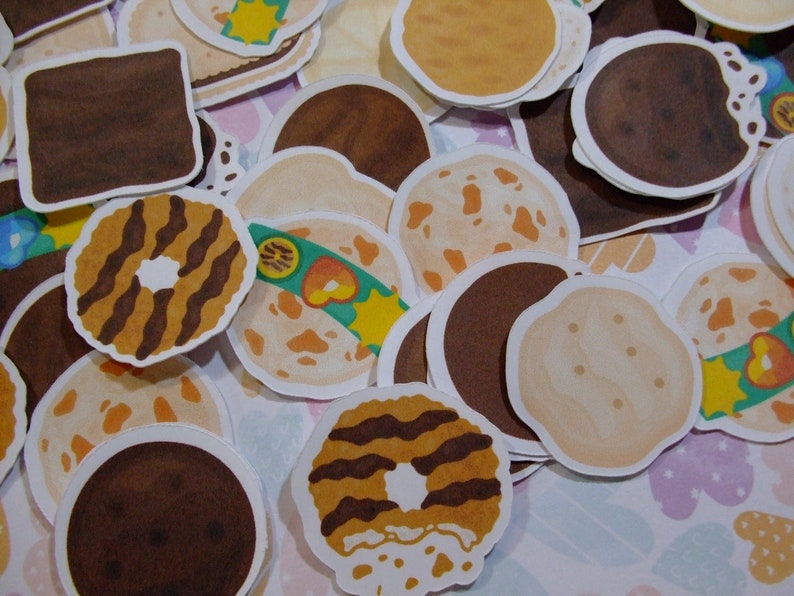 Pu&ograve; includere: Assortimento di adesivi per biscotti illustrati e colorati. Gli adesivi presentano diversi design, tra cui biscotti al cioccolato, biscotti secchi e biscotti al burro di arachidi.
