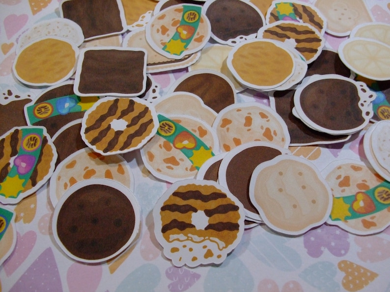 Pu&ograve; includere: Assortimento di adesivi per biscotti colorati con vari design, tra cui gocce di cioccolato, burro di arachidi e biscotti secchi. Gli adesivi sono perfetti per aggiungere un tocco di divertimento a lavoretti, pianificatori e molto altro.