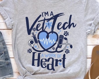 May include: A gray t-shirt with a blue graphic that says "I'm a Vet Tech A Work of Heart". The graphic includes a heart with a stethoscope, a bandage, a syringe, and paw prints.