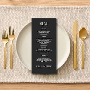 May include: A black and white wedding menu card with a modern design. The menu includes starter, main, dessert, and drinks. The card is on a beige placemat with gold silverware.