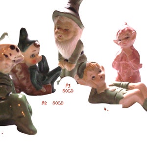 May include: A collection of vintage ceramic figurines, including gnomes and elves. The figurines are in various poses and colors, with green, pink, and brown being the dominant hues. Some figurines are marked as "Sold".