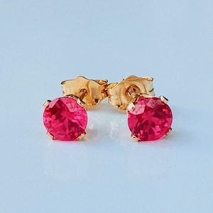 Peut inclure: Une paire de boucles d'oreilles en or avec des pierres rondes rose vif.