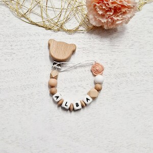 花（ピンク）とパーソナライズされた名前が付いたおしゃぶりクリップ。