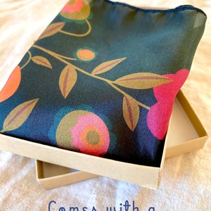 May include: A dark green silk scarf with a floral pattern in shades of pink, orange, and gold. The scarf is folded and placed in a brown gift box. "Comes with a gift box" is written in blue text on the bottom of the image.