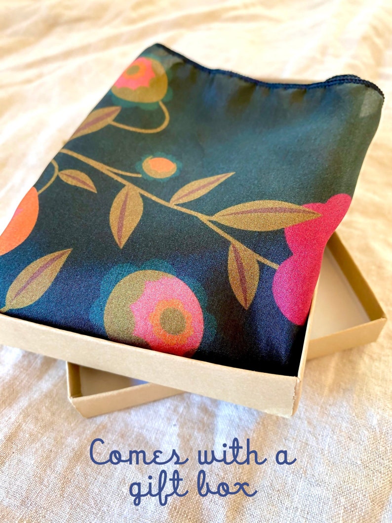 May include: A dark green silk scarf with a floral pattern in shades of pink, orange, and gold. The scarf is folded and placed in a brown gift box. "Comes with a gift box" is written in blue text on the bottom of the image.