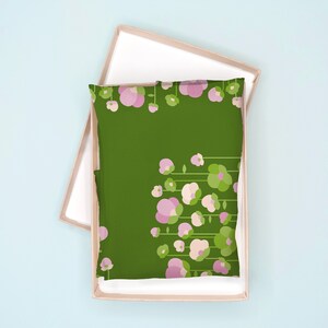 May include: A green pillowcase with a floral pattern of pink flowers and green leaves. The pillowcase is in a cardboard box.