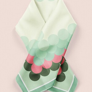 May include: A green and white silk scarf with a pattern of overlapping circles in shades of green, pink, and black. The scarf has a white border.
