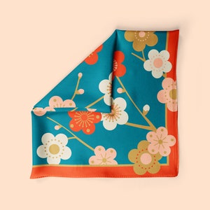 May include: A teal blue silk scarf with a floral pattern of white, pink, and red flowers. The flowers are stylized and have a gold outline. The scarf has a red border.