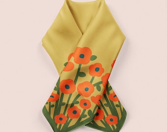 May include: Mustard yellow scarf with a floral pattern. The scarf features orange flowers with blue centers and green stems and leaves. The edges are trimmed with a dark green border. The scarf is folded and draped.