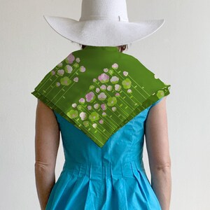 May include: A woman wearing a white sun hat and a turquoise dress with a green floral scarf.