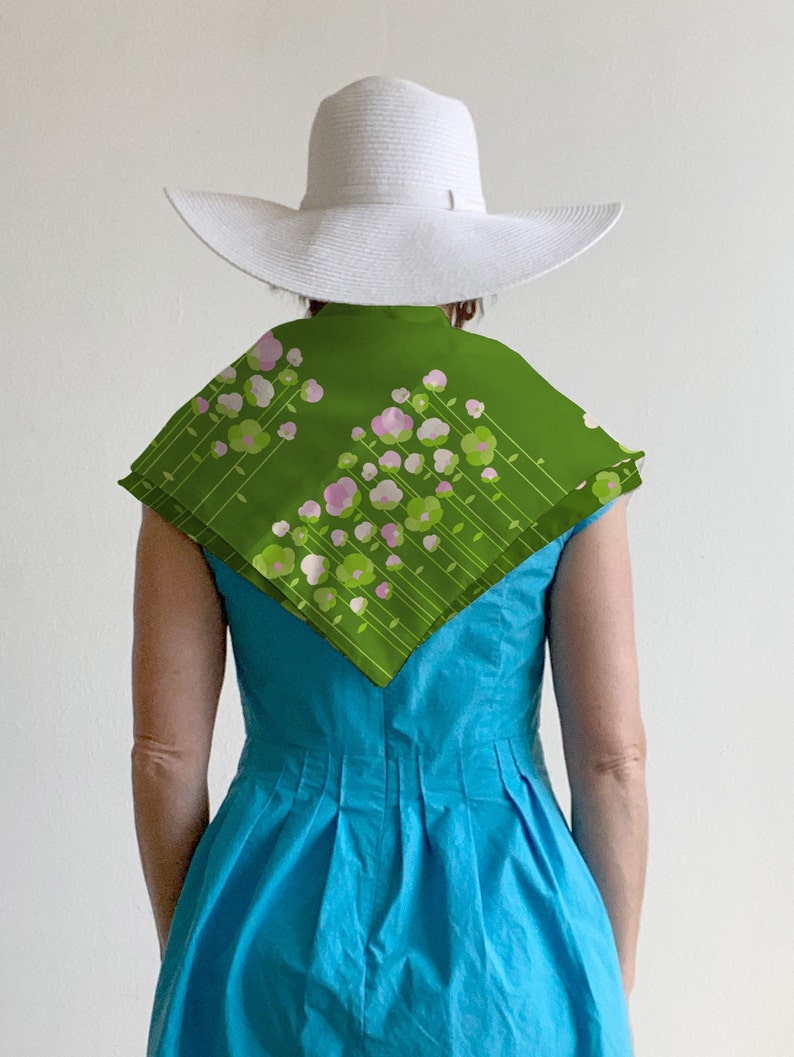 May include: A woman wearing a white sun hat and a turquoise dress with a green floral scarf.