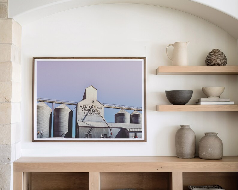 May include: A framed photograph of a grain elevator with the text "Western Mark Grain Co. Dunkirk" on the side. The photo is displayed on a shelf with other decorative items, including a pitcher, bowls, and vases.