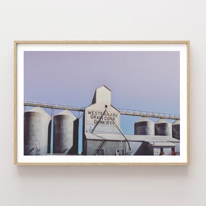 May include: A vintage photograph of a grain elevator with the text "Western Mark Grain Co. Dunkirk" on the side. The building is made of concrete and has a weathered, industrial look. The sky is a soft purple color.