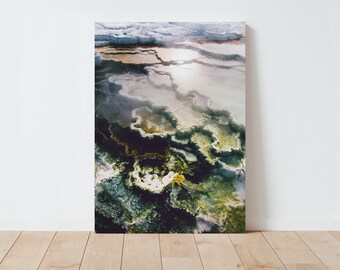 May include: Abstract aerial photograph of a natural hot spring with a swirling pattern of white, green, and yellow colors.