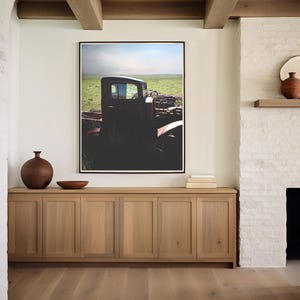 Puede incluir: Un cami&oacute;n rojo vintage en un campo, enmarcado y colgado en una pared blanca sobre un armario de madera con cuatro puertas. El armario est&aacute; en una habitaci&oacute;n con paredes de ladrillo blanco y una chimenea.