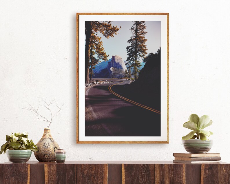 Pu&ograve; includere: Una fotografia incorniciata di una strada tortuosa che conduce a una cima di montagna nel Parco Nazionale di Yosemite. La strada &egrave; fiancheggiata da alberi e la montagna &egrave; visibile in lontananza. La fotografia &egrave; in una cornice di legno.