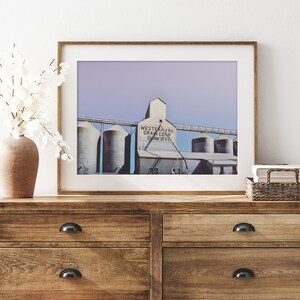 May include: A framed photograph of a grain elevator with the text "Westernark Grain Co. Dunkirk" on the side. The photo is displayed on a wooden dresser with two drawers.