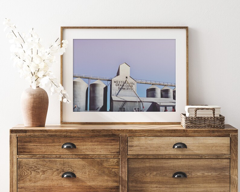 May include: A framed photograph of a grain elevator with the text "Westernark Grain Co. Dunkirk" on the side. The photo is displayed on a wooden dresser with two drawers.