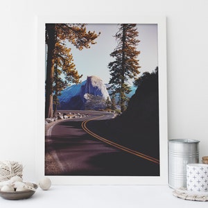 Pu&ograve; includere: Una fotografia incorniciata di una strada tortuosa che conduce a una cima di montagna nel Parco Nazionale di Yosemite. La strada &egrave; fiancheggiata da alberi e la montagna &egrave; visibile in lontananza. La foto &egrave; scattata da un angolo basso, dando allo spettatore una sensazione di prospettiva.