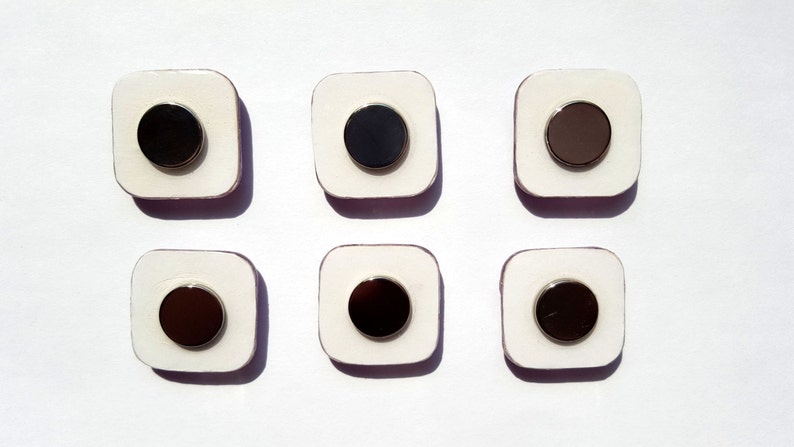 May include: Six white square tiles with a black circle in the center of each tile. The circles have a silver rim.