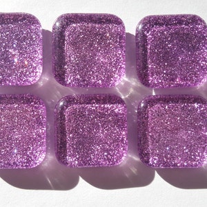 Pu&ograve; includere: Sei piastrelle di vetro quadrate con finitura glitter viola.