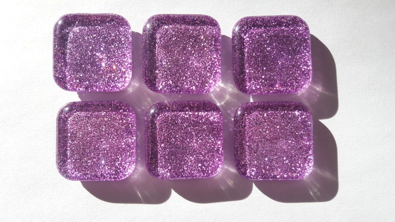 Pu&ograve; includere: Sei piastrelle di vetro quadrate con finitura glitter viola.