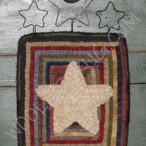 May include: A rustic, square wall hanging with a cream-colored star in the center, surrounded by concentric squares of red, blue, green, and brown. Above the hanging are three metal star cutouts and a small, dark bell.